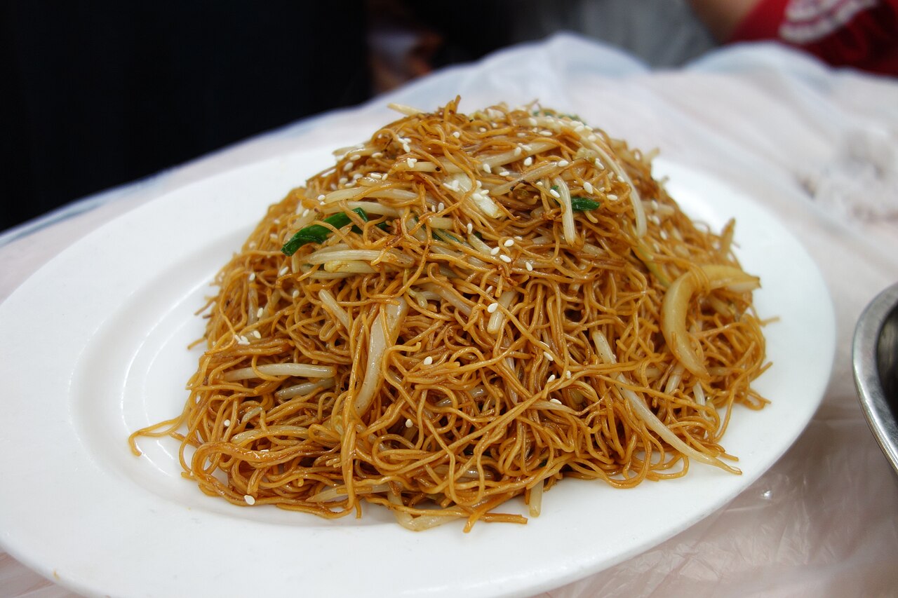 Cantonese soy sauce chow mein recipe opening image with glossy noodles, scallions, soy sauce, and wok context