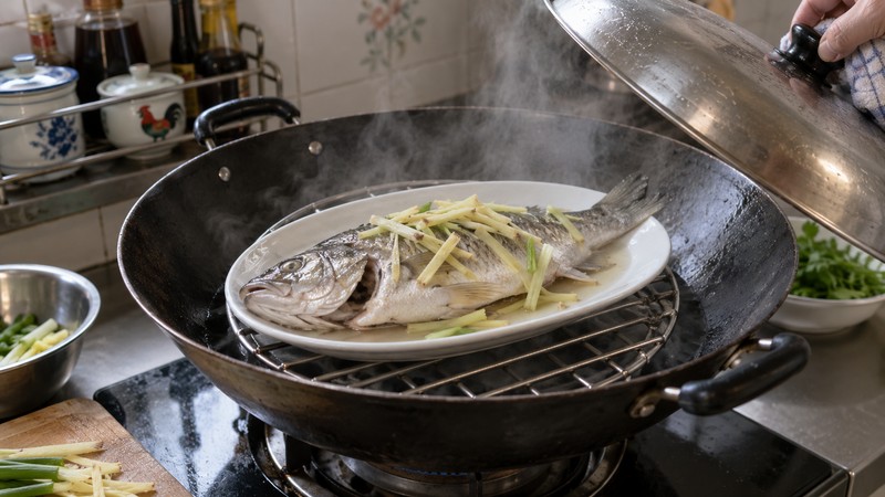 Whole fish on a heatproof plate steaming above water in a wok