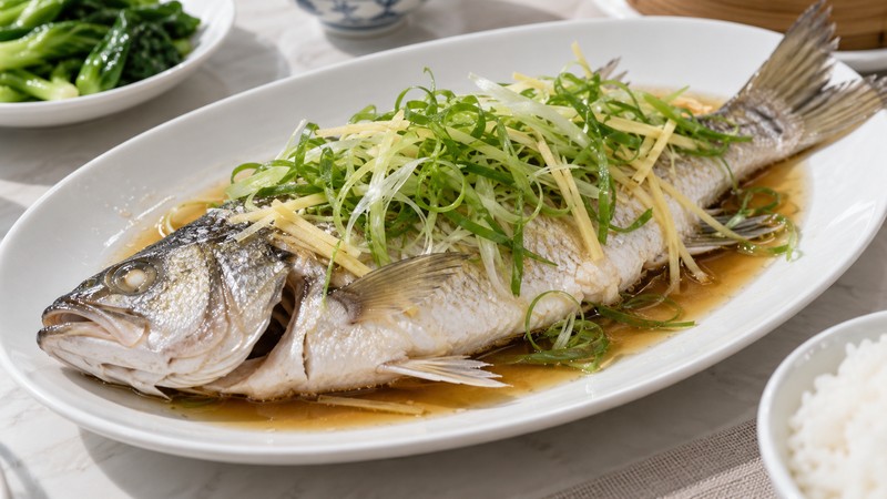 Finished Cantonese whole steamed fish with ginger scallion and light sauce
