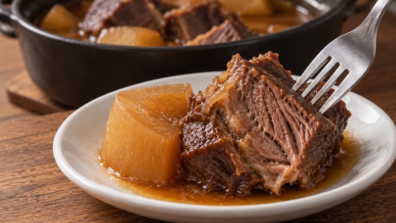A fork pressing into a cooked brisket chunk beside soft daikon