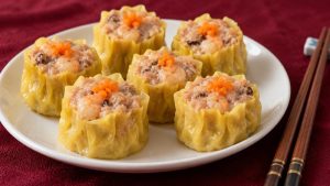 Six open-top siu mai with yellow wrappers and small carrot garnishes