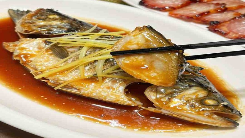 Whole cooked fish with ginger and sliced roast pork on a plate