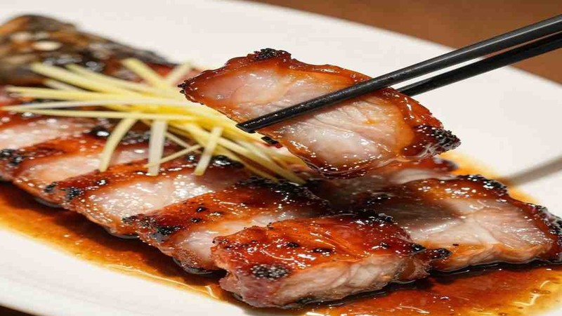 Slices of glossy roast pork on a plate