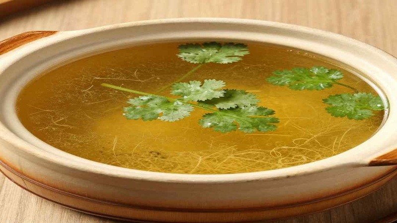 Clear soup in a shallow bowl with cilantro garnish