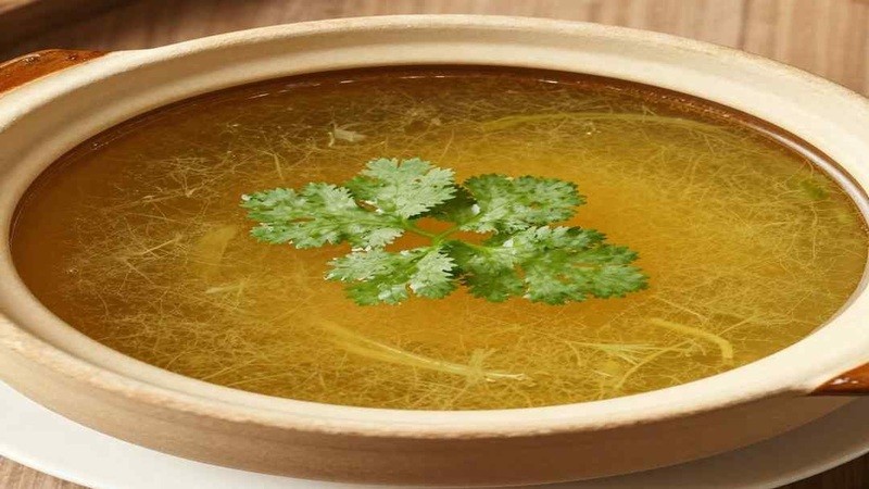 Clear soup in a shallow bowl with cilantro garnish