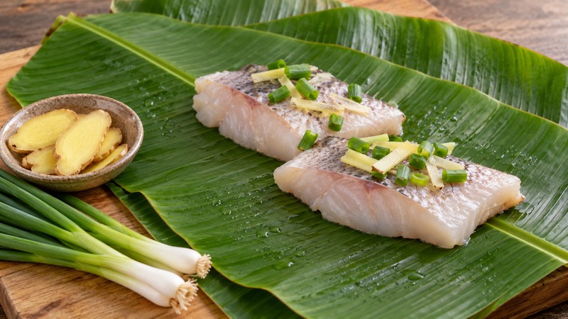 Banana leaves beside fish, ginger and scallions