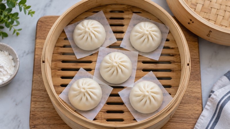 Shaped buns spaced apart on parchment squares in a steamer