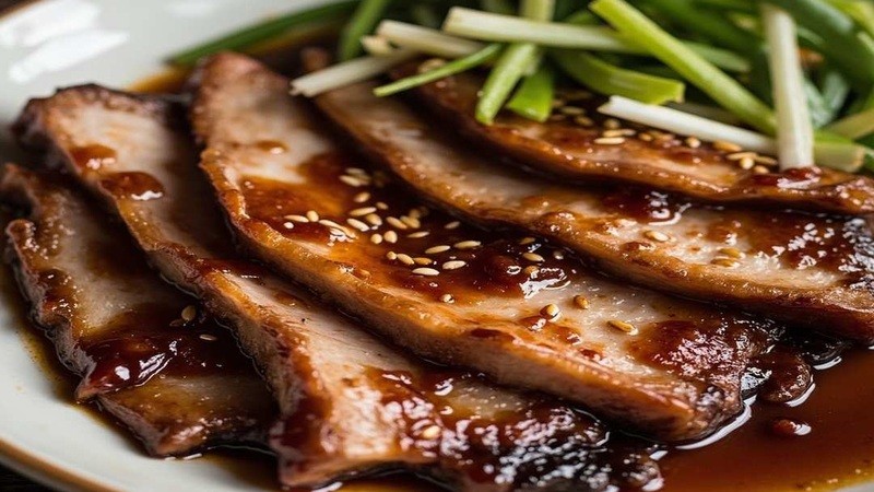 Sliced glazed pork belly with scallion and sesame garnish