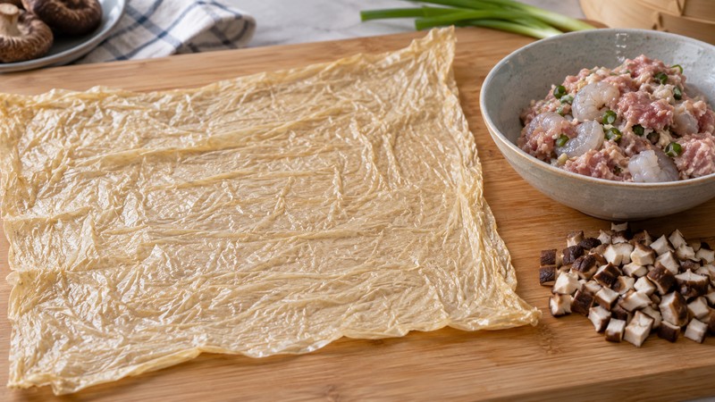 Pliable bean curd sheet beside chopped mushrooms and pork-shrimp filling