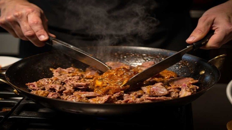 Beef slices being stirred in a wok