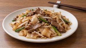 Dry-style beef chow fun showing wide rice noodle ribbons without pooled liquid