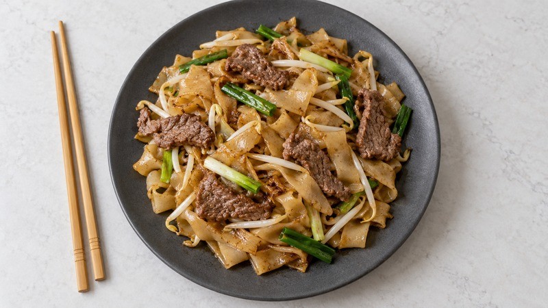 A plate of dry-style beef chow fun with broad rice noodle ribbons