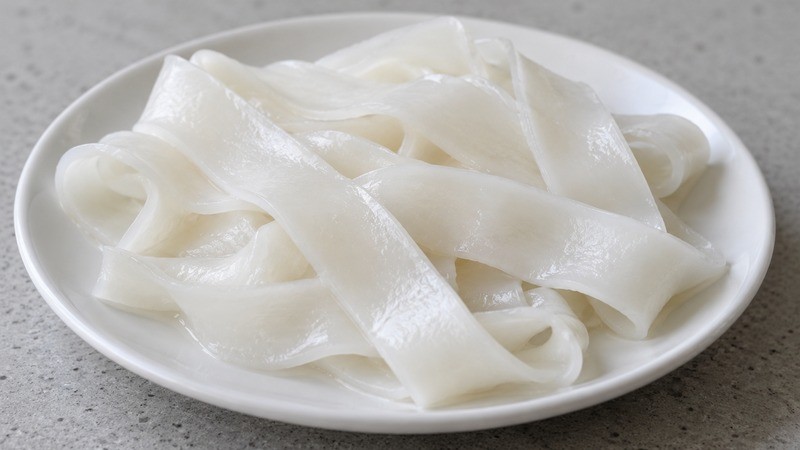 A close view of fresh white wide flat rice noodle ribbons