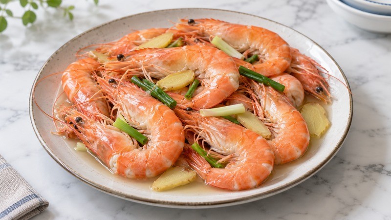 Cooked shell-on shrimp with ginger slices and scallions in a little clear cooking liquid