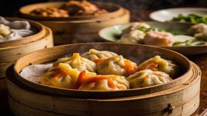 Dumplings in a bamboo steamer on a shared meal table