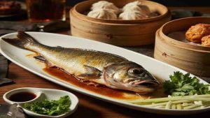 A whole fish on an oval platter with sauce and scallions