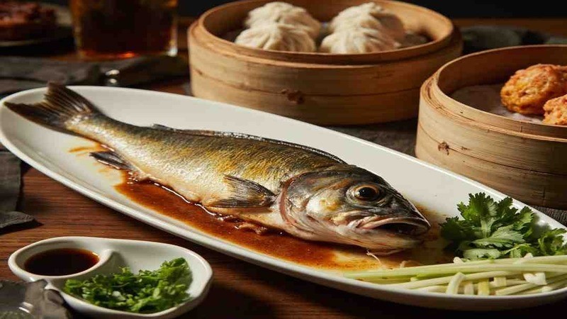 A whole fish on an oval platter with sauce and scallions