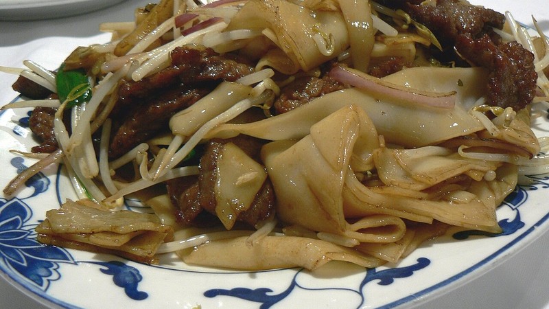 Wide rice noodles with beef and vegetables on a plate