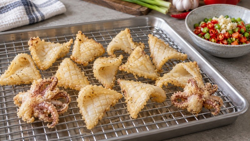 Drained fried squid on a rack before the final toss