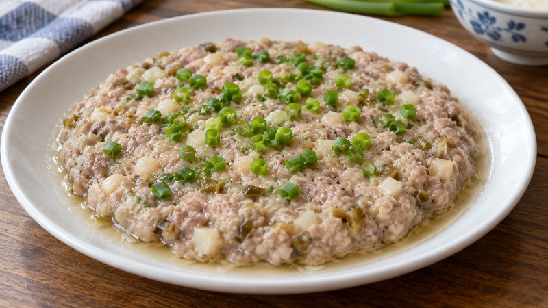 Finished shallow Cantonese steamed pork patty with water chestnut and scallion, clear meat juices at the rim