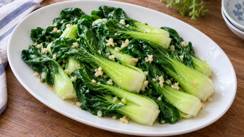 Finished glistening stir fried bok choy with garlic on a shallow oval platter