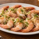 Finished ginger-scallion steamed shrimp with opaque flesh and a light soy dressing