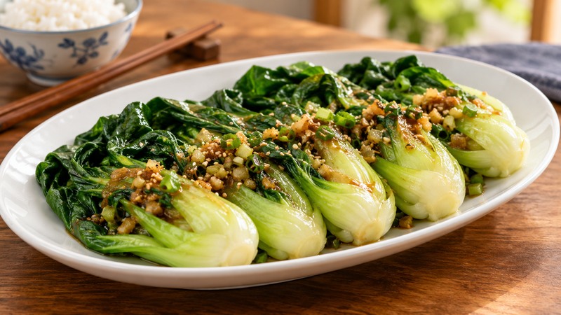 Steamed baby bok choy plated with ginger scallion soy sauce and sesame seeds